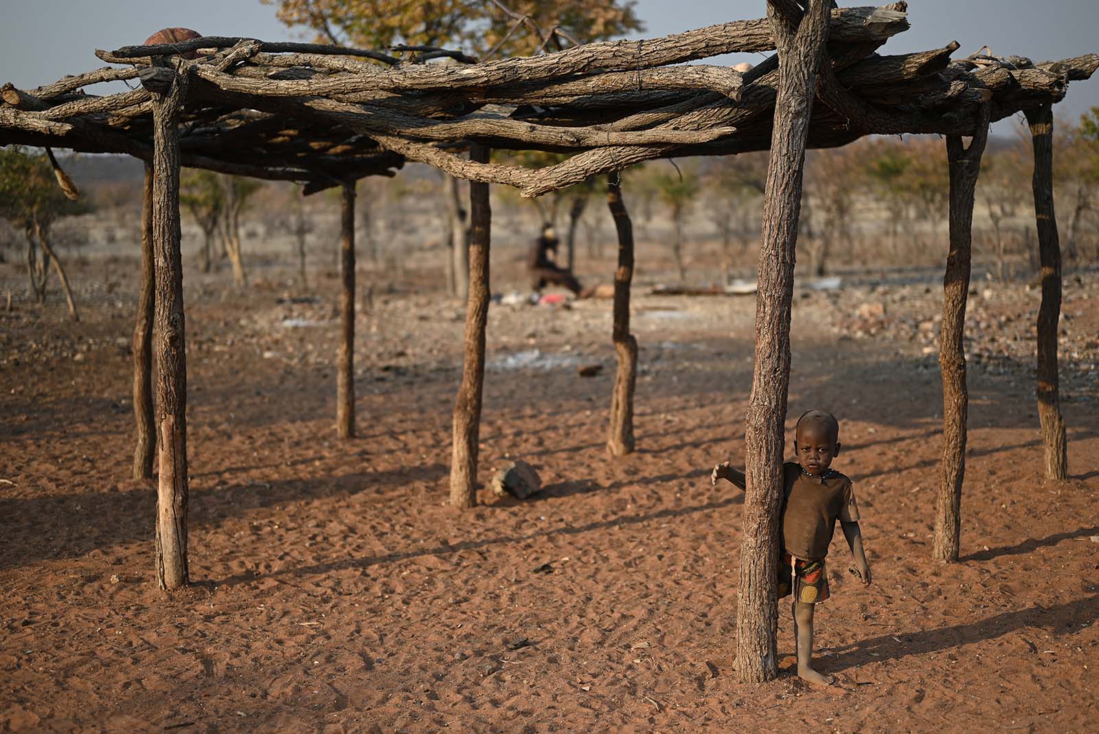 Himba Kind steht an Pfosten eines Unterstandes