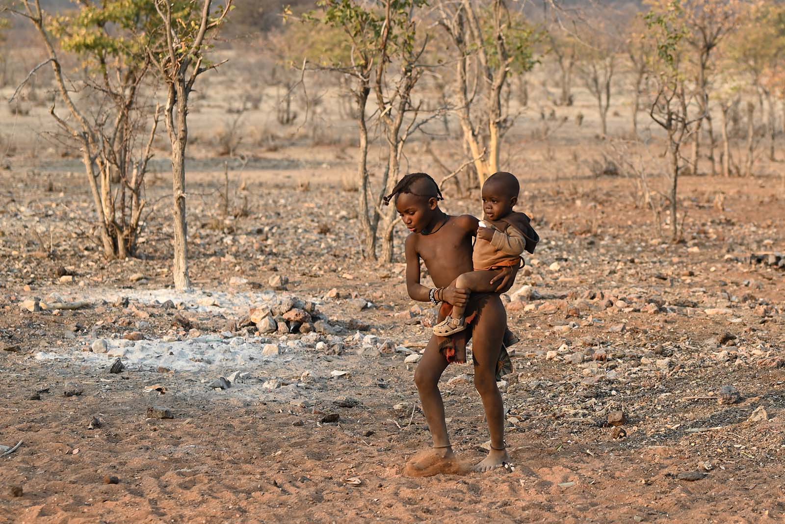 Älteres Himba Kind trägt ein jüngeres auf dem Arm